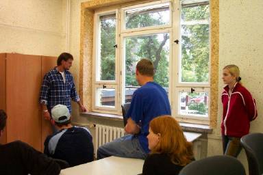 Einer unserer Malermeister, der Kollege Oberländer, und die Klasse MDQM II, 2. Ausbildungsjahr, 2004/05, besichtigen die zu renovierenden Holzfenster, begutachten ihren Zustand und entscheiden, welche Arbeiten im Einzelnen durchgeführt werden sollen.